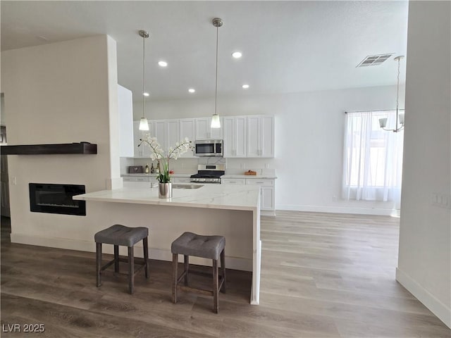 8545 Summer Vista Ave, Las Vegas, NV 89145 - kitchen featuring appliances with stainless steel finishes, baseboards, white cabinets, a breakfast bar, and light wood finished floors