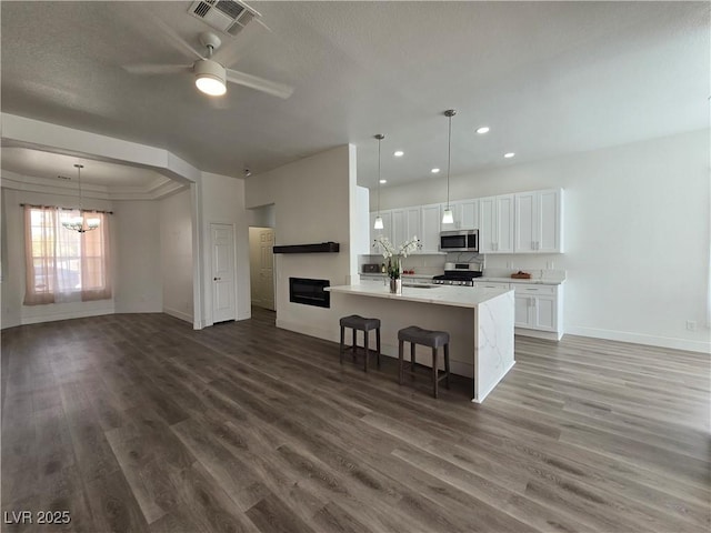 8545 Summer Vista Ave, Las Vegas, NV 89145 - kitchen with appliances with stainless steel finishes, baseboards, wood finished floors, a breakfast bar area, and recessed lighting