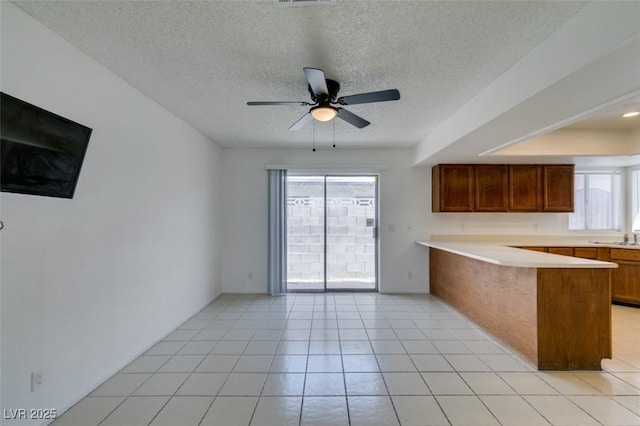 2116 Cameron St, Las Vegas, NV 89102 - kitchen featuring a peninsula, plenty of natural light, ceiling fan, brown cabinetry, and a textured ceiling