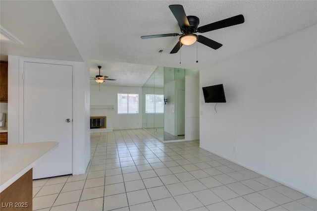 2116 Cameron St, Las Vegas, NV 89102 - unfurnished room with ceiling fan, a textured ceiling, a fireplace, and light tile patterned floors