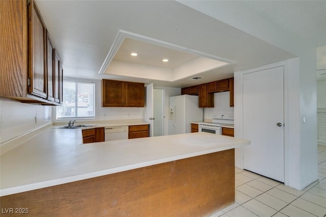2116 Cameron St, Las Vegas, NV 89102 - kitchen with white appliances, a raised ceiling, a peninsula, light countertops, and a sink