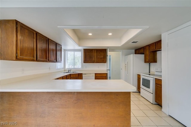 2116 Cameron St, Las Vegas, NV 89102 - kitchen featuring white appliances, a peninsula, light countertops, light tile patterned floors, and a tray ceiling