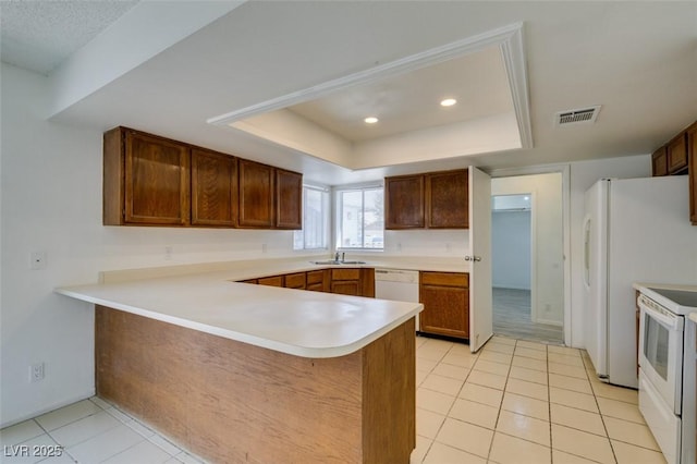 2116 Cameron St, Las Vegas, NV 89102 - kitchen with white appliances, light tile patterned floors, a tray ceiling, light countertops, and a peninsula