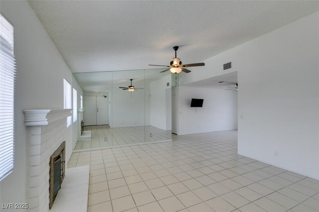 2116 Cameron St, Las Vegas, NV 89102 - unfurnished living room featuring ceiling fan, a brick fireplace, a textured ceiling, and light tile patterned flooring