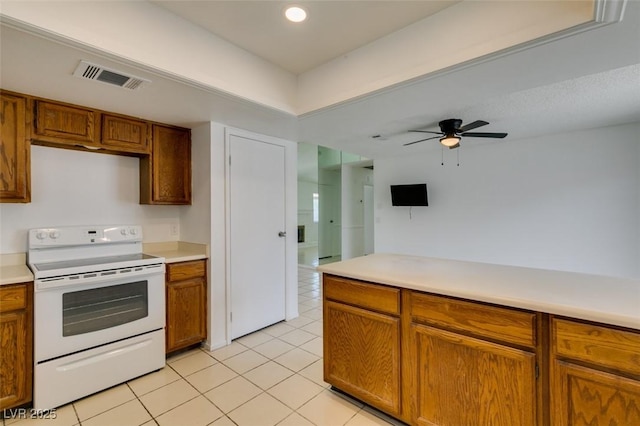 2116 Cameron St, Las Vegas, NV 89102 - kitchen with white range with electric stovetop, light tile patterned floors, brown cabinetry, light countertops, and recessed lighting