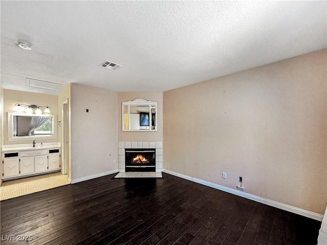 2204 Short Pine Dr, Las Vegas, NV 89108 - unfurnished living room with hardwood / wood-style flooring, baseboards, a textured ceiling, a fireplace, and a sink