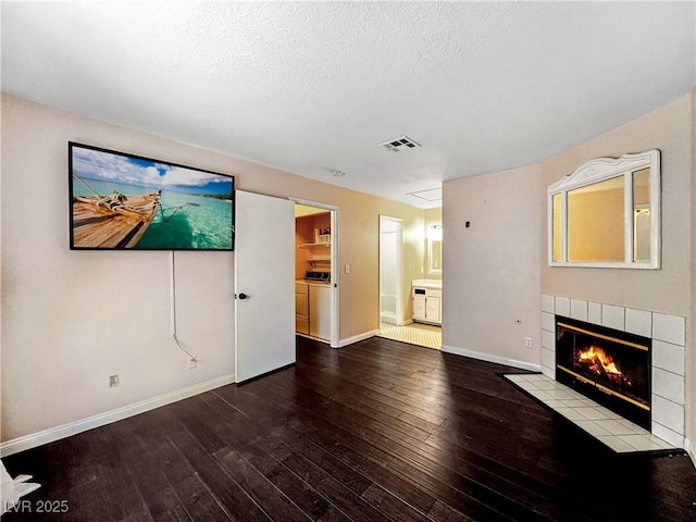 2204 Short Pine Dr, Las Vegas, NV 89108 - unfurnished living room featuring hardwood / wood-style floors, a tile fireplace, washer and clothes dryer, baseboards, and a textured ceiling