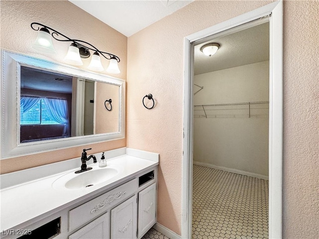 2204 Short Pine Dr, Las Vegas, NV 89108 - bathroom featuring a textured wall, vanity, and a walk in closet