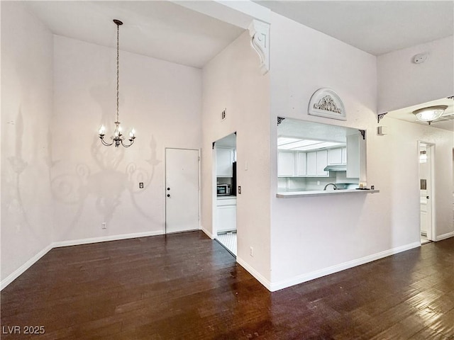 2204 Short Pine Dr, Las Vegas, NV 89108 - unfurnished living room with a high ceiling, dark wood finished floors, a chandelier, and baseboards