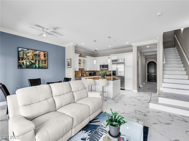 30 Via Vasari Unit 103, Henderson, NV 89011 - living room featuring a ceiling fan, stairs, crown molding, arched walkways, and light marble finish flooring