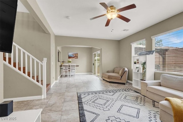 8015 Maple Park St, Las Vegas, NV 89131 - living room featuring arched walkways, a ceiling fan, baseboards, stairway, and light tile patterned floors
