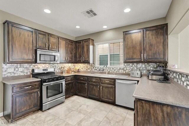 8015 Maple Park St, Las Vegas, NV 89131 - kitchen featuring stainless steel appliances, a sink, dark brown cabinets, backsplash, and light countertops
