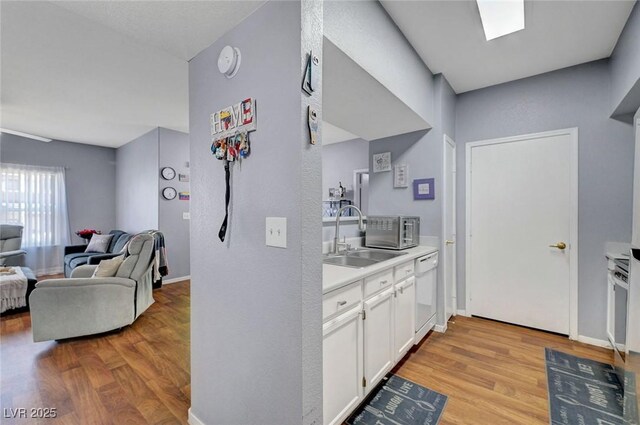 6650 W Warm Springs Rd Unit 1083, Las Vegas, NV 89118 - kitchen featuring a sink, dishwasher, light wood-type flooring, and white cabinets