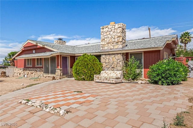 812 Pyramid Dr, Las Vegas, NV 89107 - view of front of property with a chimney, stone siding, a shingled roof, and a patio