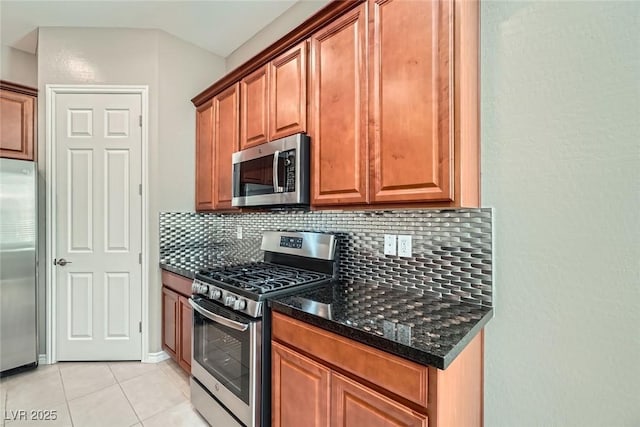 208 Coltrane Canyon Ave, Henderson, NV 89011 - kitchen with appliances with stainless steel finishes, decorative backsplash, light tile patterned floors, dark stone counters, and brown cabinetry