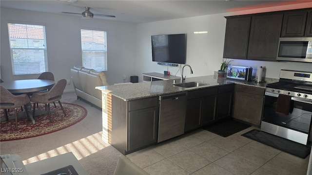 5209 Silica Chalk Ave, Las Vegas, NV 89115 - kitchen featuring appliances with stainless steel finishes, a peninsula, light stone counters, a ceiling fan, and open floor plan