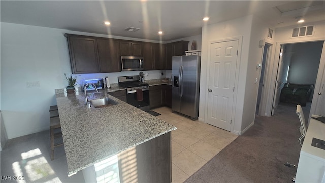 5209 Silica Chalk Ave, Las Vegas, NV 89115 - kitchen with stainless steel appliances, a peninsula, light stone counters, dark brown cabinets, and light tile patterned floors