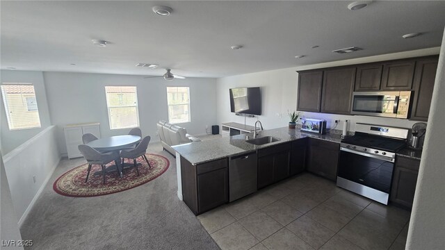 5209 Silica Chalk Ave, Las Vegas, NV 89115 - kitchen with stainless steel appliances, a peninsula, open floor plan, light stone countertops, and ceiling fan