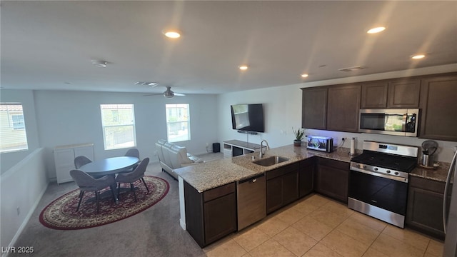 5209 Silica Chalk Ave, Las Vegas, NV 89115 - kitchen featuring stainless steel appliances, a peninsula, dark brown cabinetry, light stone countertops, and recessed lighting