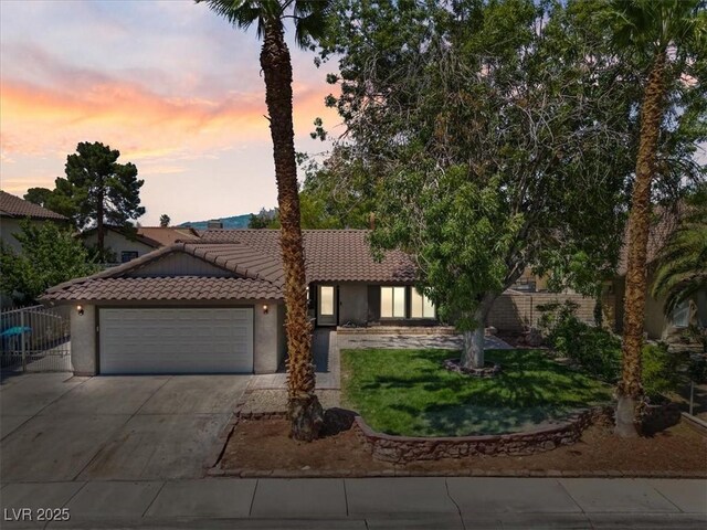 6436 Vinecrest Ave, Las Vegas, NV 89108 - view of front of house featuring a tiled roof, a garage, driveway, stucco siding, and a yard