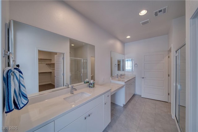 5091 E Beacon Ridge Dr, Pahrump, NV 89061 - bathroom with a shower stall, two vanities, a walk in closet, recessed lighting, and tile patterned flooring