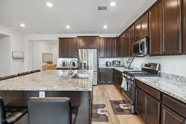 7616 Quail Dust St, North Las Vegas, NV 89084 - kitchen with appliances with stainless steel finishes, light wood-type flooring, a kitchen breakfast bar, a sink, and recessed lighting