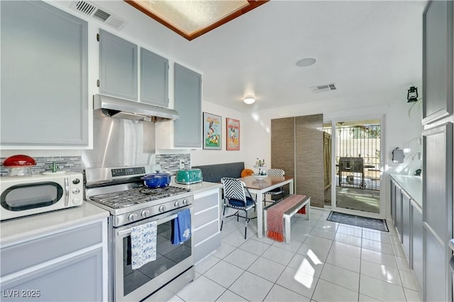 4629 Denwood Dr, Las Vegas, NV 89147 - kitchen featuring gas stove, range hood, white microwave, decorative backsplash, and light tile patterned floors