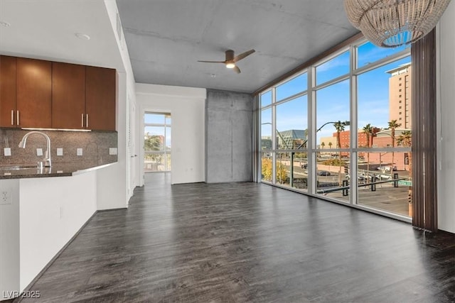 353 E Bonneville Ave Unit 313, Las Vegas, NV 89101 - unfurnished living room featuring a sink, dark wood-type flooring, ceiling fan, a chandelier, and expansive windows
