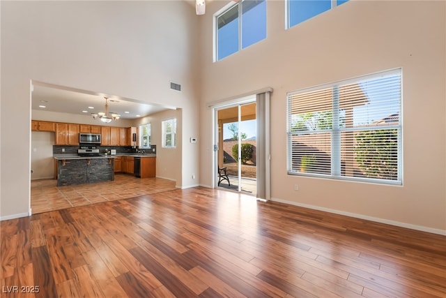2608 Campobello Ave, North Las Vegas, NV 89081 - unfurnished living room featuring a chandelier, light wood finished floors, baseboards, and a high ceiling