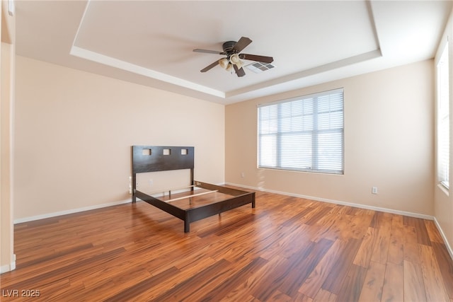 2608 Campobello Ave, North Las Vegas, NV 89081 - unfurnished bedroom featuring a raised ceiling, wood finished floors, multiple windows, and baseboards