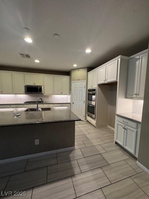 4108 Fairywren Dr, North Las Vegas, NV 89031 - kitchen with stainless steel appliances, dark stone countertops, decorative backsplash, a sink, and recessed lighting