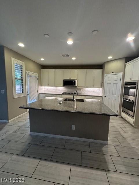 4108 Fairywren Dr, North Las Vegas, NV 89031 - kitchen with stainless steel appliances, dark stone counters, a sink, white cabinetry, and baseboards