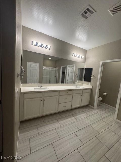 4108 Fairywren Dr, North Las Vegas, NV 89031 - bathroom with double vanity, a stall shower, toilet, baseboards, and a textured ceiling