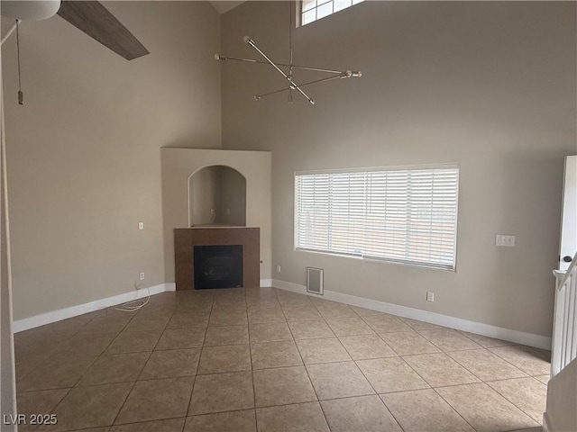 2025 Cary Grant Ct, Las Vegas, NV 89142 - unfurnished living room with a high ceiling, a fireplace, tile patterned flooring, ceiling fan, and baseboards