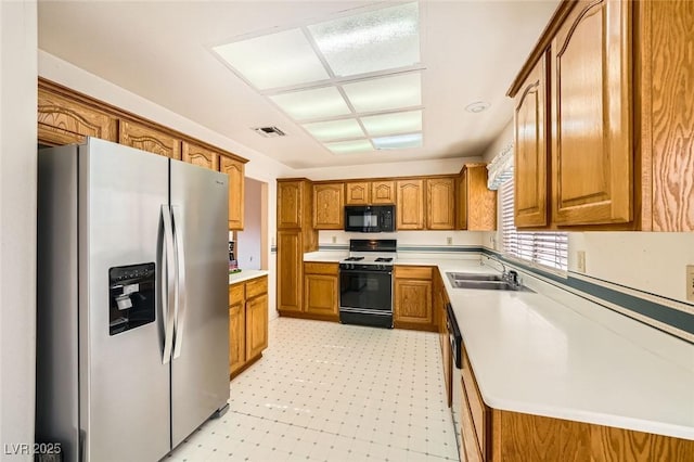 3104 Hayden Ct, Las Vegas, NV 89134 - kitchen featuring stainless steel refrigerator with ice dispenser, range, black microwave, brown cabinets, and light flooring