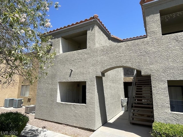3151 Soaring Gulls Dr Unit 2147, Las Vegas, NV 89128 - view of property exterior featuring stucco siding, cooling unit, a tile roof, and stairs