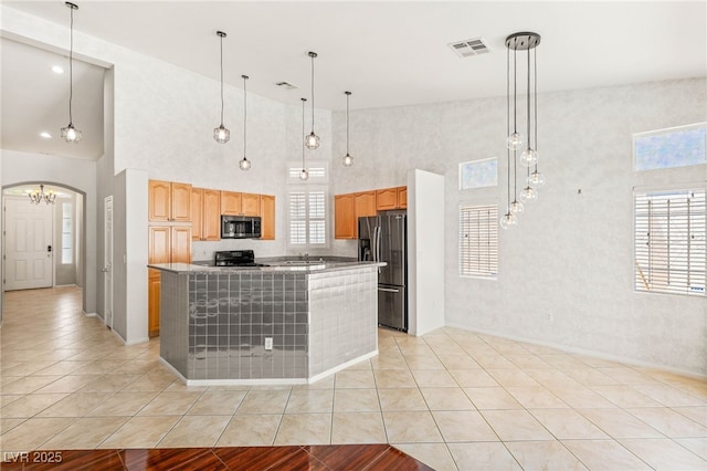 9688 Meeks Bay Ave, Las Vegas, NV 89148 - kitchen featuring stainless steel appliances, a towering ceiling, a kitchen island, light brown cabinets, and arched walkways