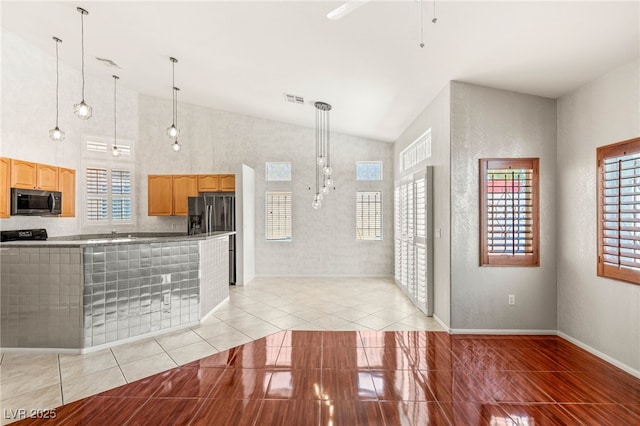 9688 Meeks Bay Ave, Las Vegas, NV 89148 - kitchen featuring stainless steel appliances, light tile patterned floors, light brown cabinetry, hanging light fixtures, and vaulted ceiling