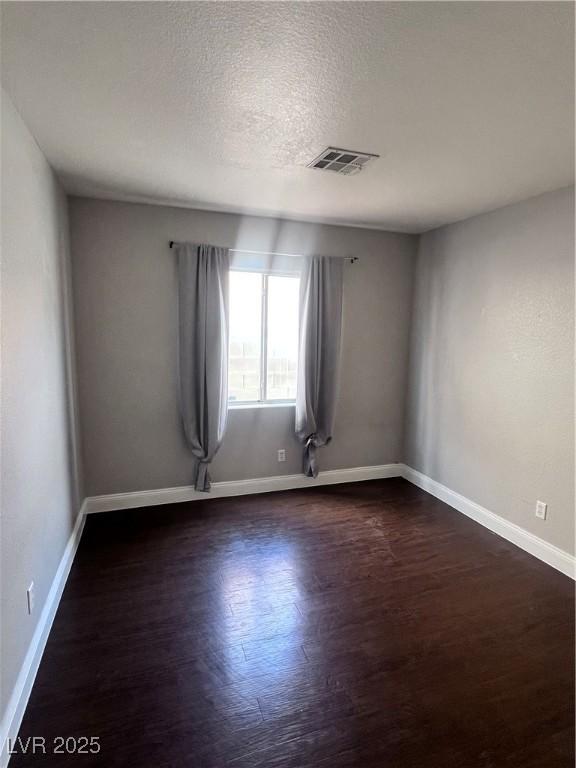 5217 Yellow Dawn Ct, Las Vegas, NV 89130 - unfurnished room featuring dark wood-style floors, baseboards, and a textured ceiling