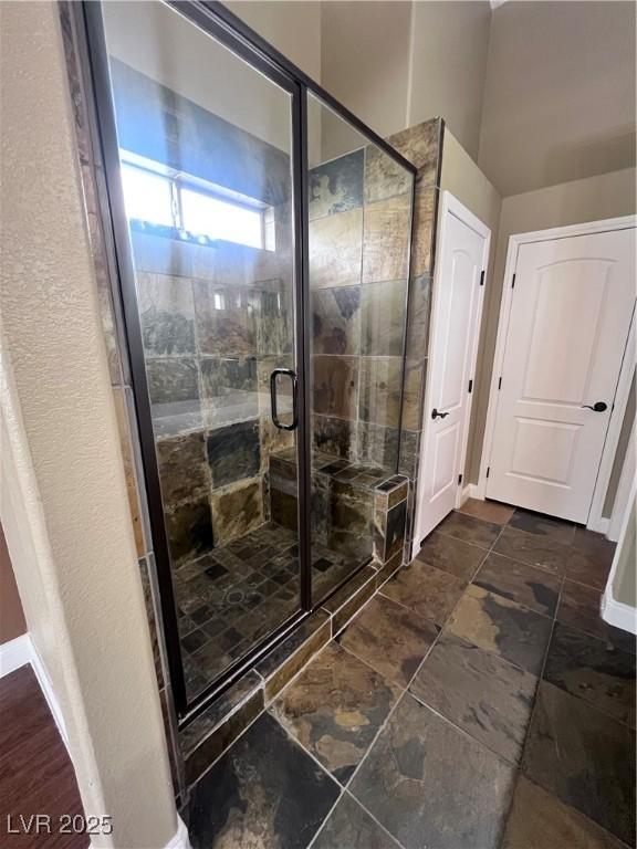 5217 Yellow Dawn Ct, Las Vegas, NV 89130 - bathroom featuring a stall shower, baseboards, and stone finish flooring