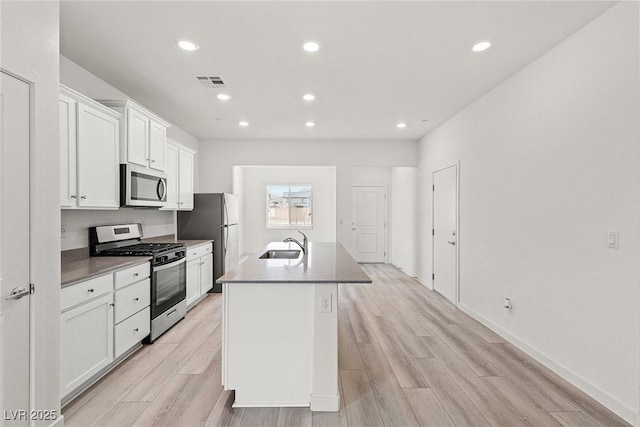 2751 Avril Point St, Las Vegas, NV 89156 - kitchen featuring appliances with stainless steel finishes, a kitchen island with sink, a sink, white cabinetry, and light wood-style flooring