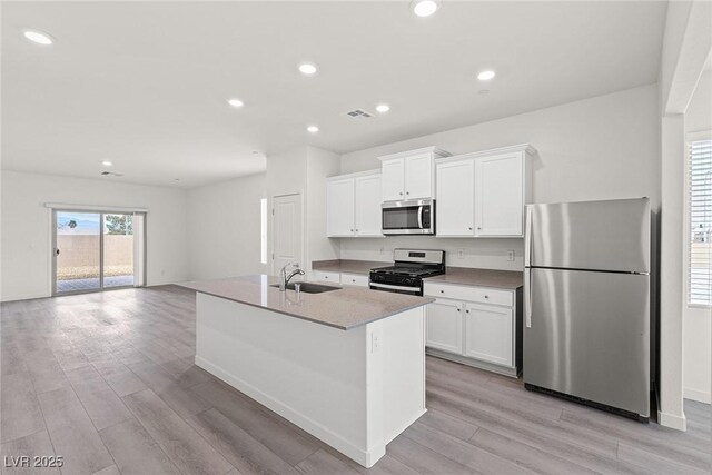 2751 Avril Point St, Las Vegas, NV 89156 - kitchen featuring appliances with stainless steel finishes, a sink, light wood-style floors, a center island with sink, and white cabinetry