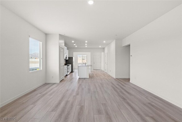 2751 Avril Point St, Las Vegas, NV 89156 - unfurnished living room with recessed lighting, light wood-style flooring, baseboards, and a sink