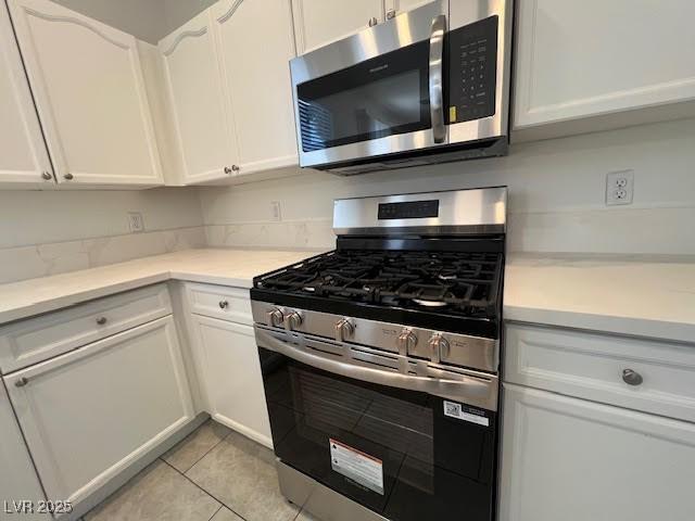 1030 Country Skies Ave, Las Vegas, NV 89123 - kitchen featuring stainless steel appliances, white cabinetry, light tile patterned floors, and light countertops