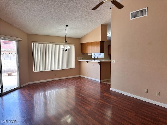 6600 Silver Penny Ave, Las Vegas, NV 89108 - unfurnished living room featuring vaulted ceiling, dark wood-style flooring, baseboards, a textured ceiling, and a chandelier
