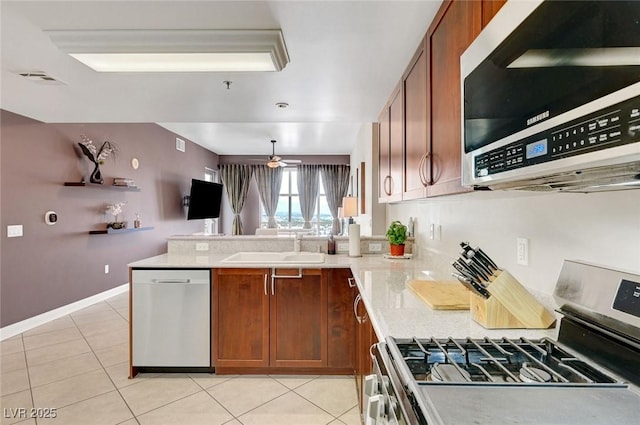 150 Las Vegas Blvd Unit 1503, Las Vegas, NV 89101 - kitchen featuring appliances with stainless steel finishes, brown cabinets, a peninsula, a sink, and light tile patterned floors
