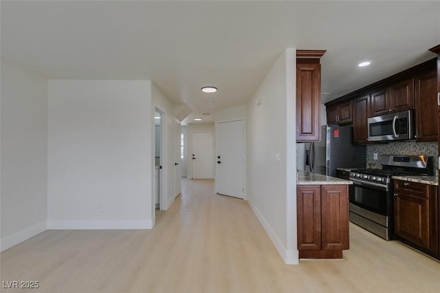 5330 E Charleston Blvd Unit 2, Las Vegas, NV 89142 - kitchen with stainless steel appliances, light wood-style flooring, decorative backsplash, light stone counters, and baseboards