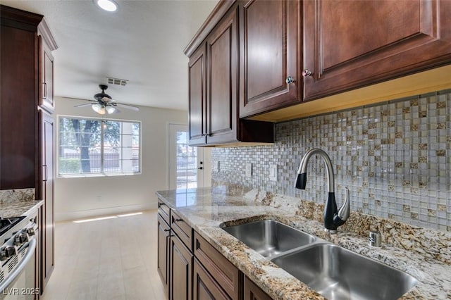 5330 E Charleston Blvd Unit 2, Las Vegas, NV 89142 - kitchen featuring a sink, stainless steel gas stove, tasteful backsplash, a ceiling fan, and light stone counters