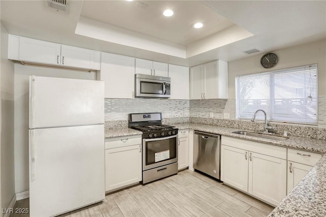 5132 Springland St, Las Vegas, NV 89146 - kitchen with stainless steel appliances, a sink, a raised ceiling, white cabinets, and recessed lighting