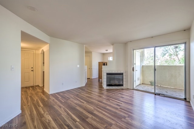 698 S Racetrack Rd Unit 1014, Henderson, NV 89015 - unfurnished living room featuring wood finished floors, a tile fireplace, baseboards, and arched walkways